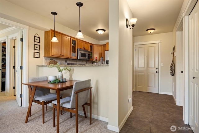 dining space with baseboards and dark tile patterned floors