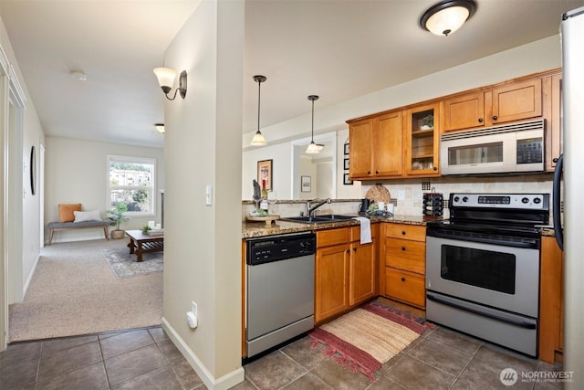 kitchen featuring brown cabinets, appliances with stainless steel finishes, glass insert cabinets, and a sink