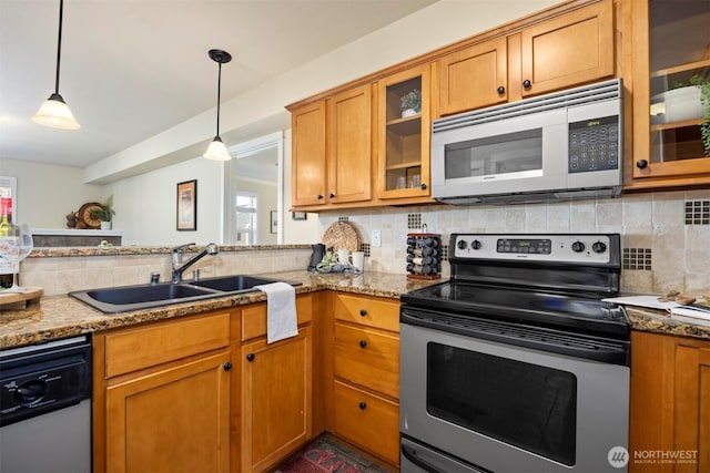 kitchen featuring tasteful backsplash, brown cabinets, appliances with stainless steel finishes, hanging light fixtures, and a sink