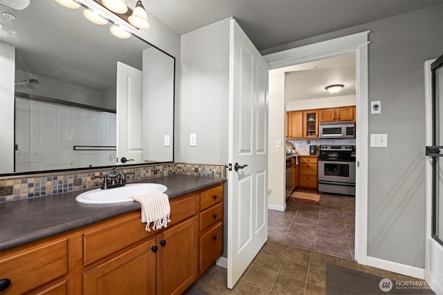 bathroom with baseboards, decorative backsplash, tile patterned floors, vanity, and a shower