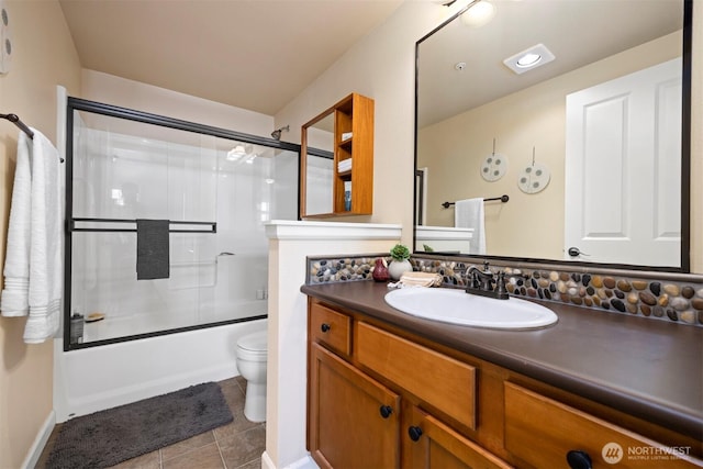 bathroom featuring tile patterned floors, bath / shower combo with glass door, toilet, and vanity