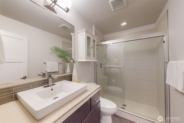 bathroom featuring visible vents, toilet, a stall shower, and vanity