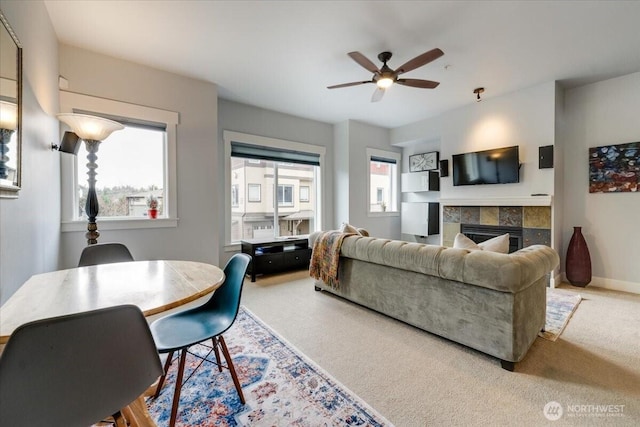 living room featuring carpet flooring, a fireplace, baseboards, and ceiling fan