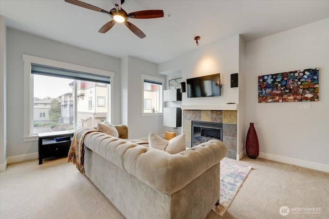 living room with light carpet, a ceiling fan, baseboards, and a tile fireplace