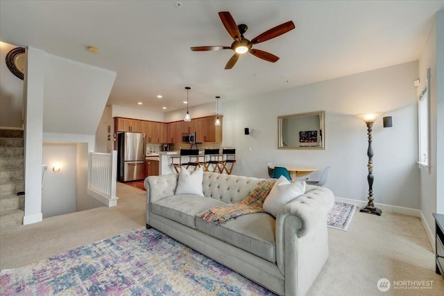 living area featuring baseboards, ceiling fan, stairway, light carpet, and recessed lighting