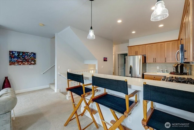 kitchen with recessed lighting, stainless steel appliances, baseboards, light colored carpet, and hanging light fixtures