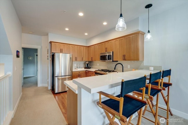 kitchen featuring a breakfast bar, backsplash, stainless steel appliances, a peninsula, and light countertops