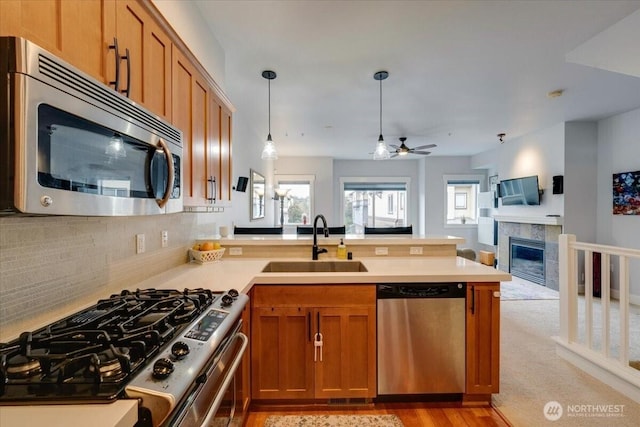 kitchen with a sink, a peninsula, brown cabinetry, and stainless steel appliances