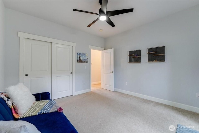 bedroom featuring light colored carpet, baseboards, a closet, and ceiling fan