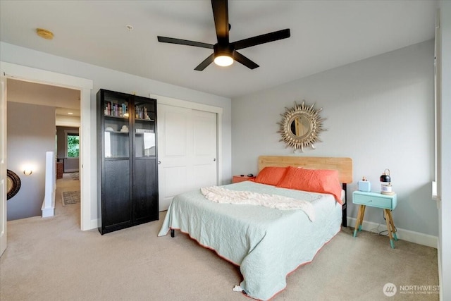 bedroom with a ceiling fan, light colored carpet, a closet, and baseboards