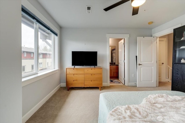 bedroom with visible vents, baseboards, light carpet, ensuite bath, and a ceiling fan