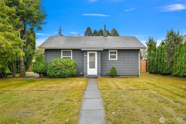 view of front facade featuring a front yard, fence, and a chimney