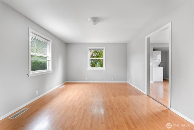 unfurnished room featuring visible vents, baseboards, light wood-style floors, and stacked washer / dryer