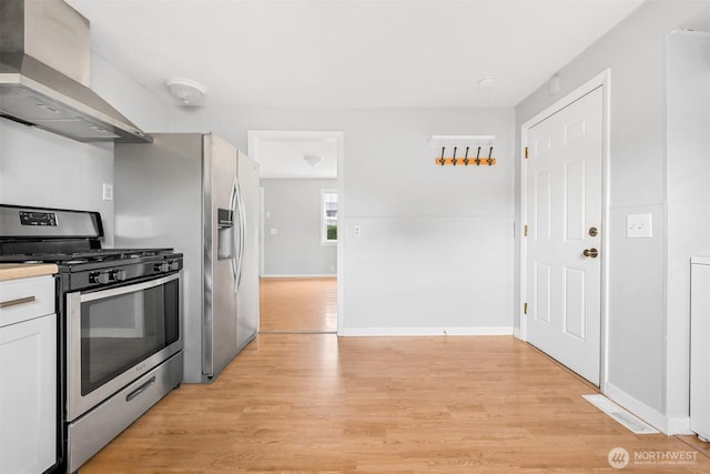 kitchen with light countertops, wall chimney exhaust hood, light wood-type flooring, and stainless steel range with gas cooktop