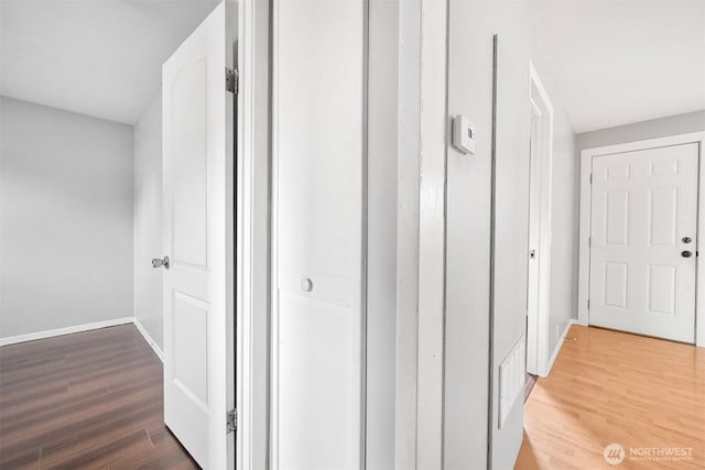 corridor with baseboards and wood finished floors