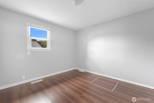 spare room featuring visible vents, dark wood-style floors, and baseboards