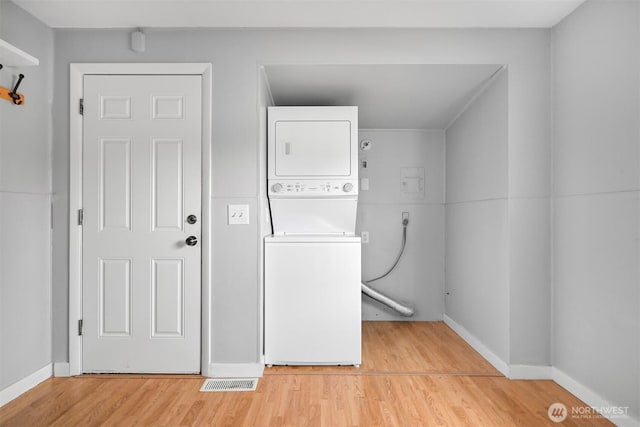 washroom with baseboards, visible vents, laundry area, light wood-style flooring, and stacked washer and dryer