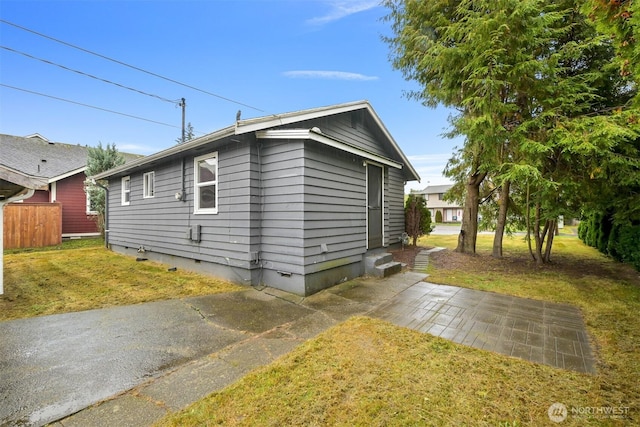 view of side of home with crawl space, fence, a yard, and entry steps