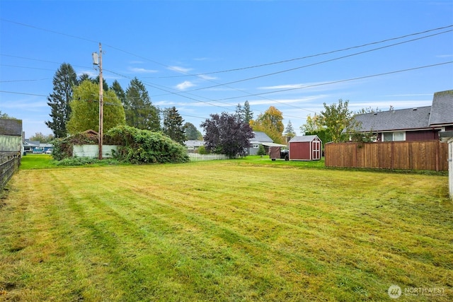 view of yard with a storage shed, an outdoor structure, and fence