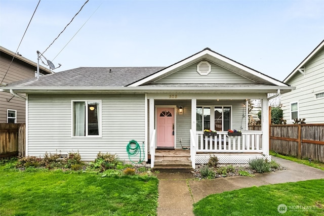 view of front of home with roof with shingles, a porch, a front lawn, and fence