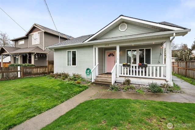 view of front of property featuring covered porch, a front yard, and fence