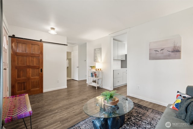 living area with baseboards, a barn door, and wood finished floors