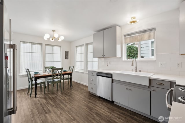 kitchen featuring dishwasher, decorative backsplash, gray cabinets, range with electric stovetop, and a sink