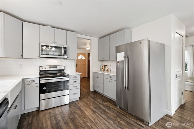 kitchen featuring stainless steel appliances, backsplash, dark wood finished floors, and light countertops