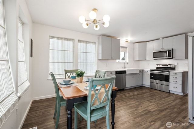 kitchen with dark wood-type flooring, appliances with stainless steel finishes, gray cabinets, and light countertops