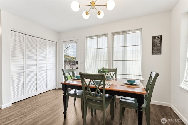 dining area featuring a chandelier, baseboards, and wood finished floors