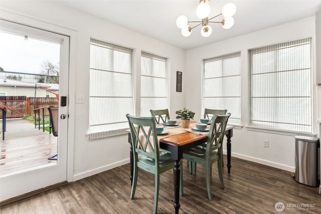 dining area featuring a healthy amount of sunlight, baseboards, an inviting chandelier, and wood finished floors