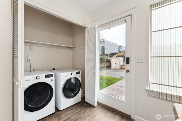 clothes washing area featuring wood finished floors, separate washer and dryer, and laundry area