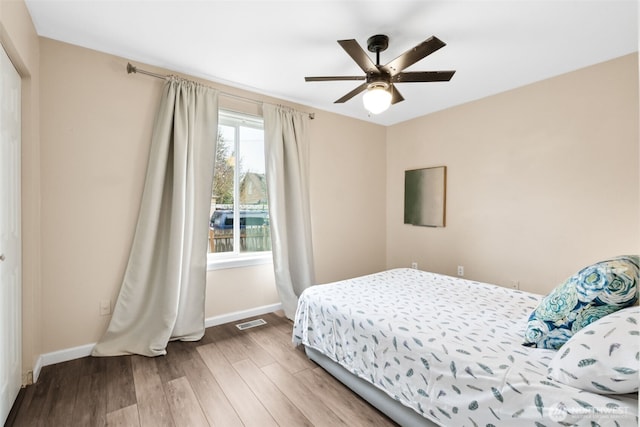 bedroom with visible vents, a ceiling fan, baseboards, and wood finished floors