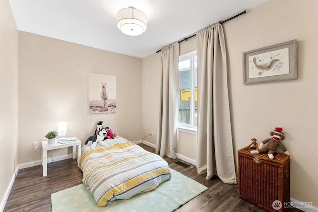 bedroom with visible vents, wood finished floors, and baseboards