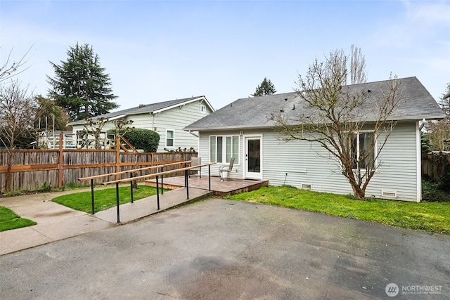 back of property with fence, a wooden deck, a shingled roof, crawl space, and a patio area