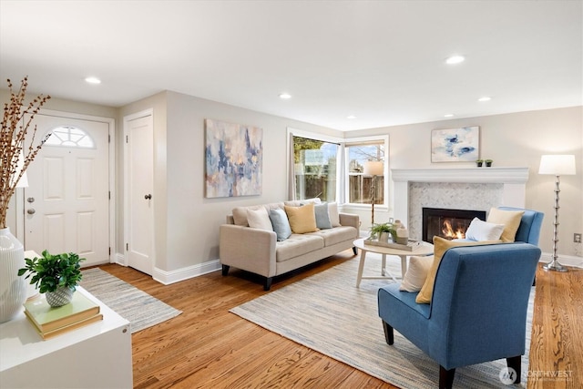 living area with a glass covered fireplace, recessed lighting, baseboards, and wood finished floors