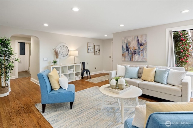 living area with arched walkways, recessed lighting, and wood finished floors