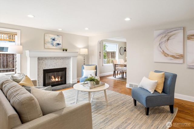 living room with a tiled fireplace, recessed lighting, baseboards, and wood finished floors