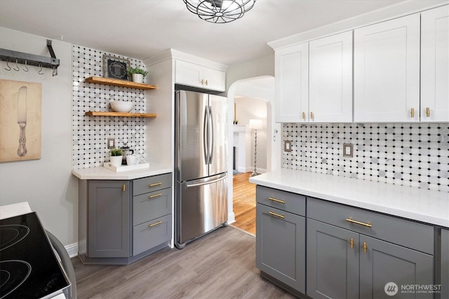 kitchen featuring arched walkways, tasteful backsplash, gray cabinets, and freestanding refrigerator