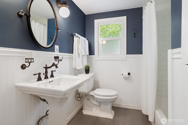 bathroom with wainscoting, toilet, and a shower with shower curtain