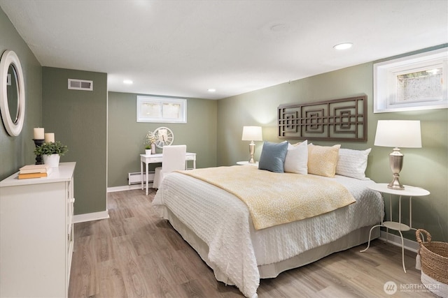 bedroom with visible vents, baseboards, baseboard heating, and light wood-style flooring