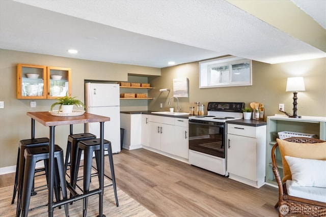 kitchen with open shelves, light wood-style flooring, freestanding refrigerator, a sink, and electric stove