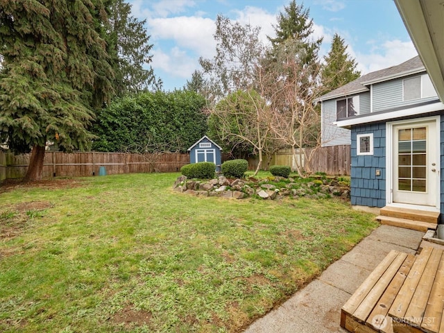 view of yard with an outbuilding, a shed, entry steps, and a fenced backyard