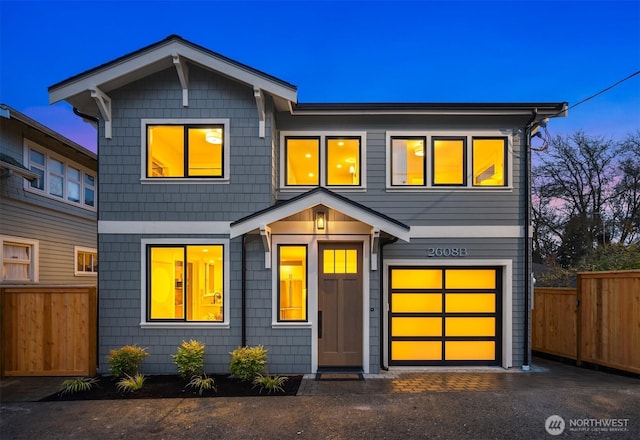 view of front of property featuring an attached garage, fence, and driveway