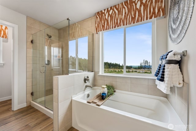 bathroom with a shower stall, a bath, and wood finished floors