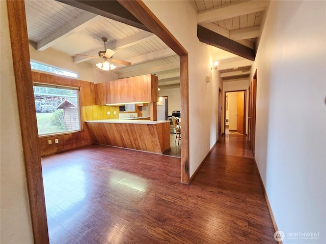 kitchen featuring dark wood-style floors, baseboards, a peninsula, beam ceiling, and light countertops