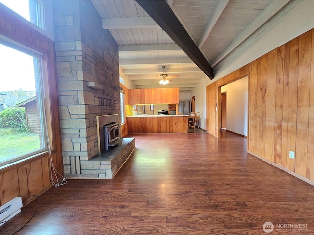 unfurnished living room with wood walls, wood finished floors, a wood stove, and a baseboard radiator