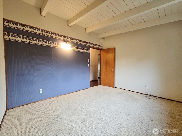 spare room featuring beamed ceiling and carpet flooring