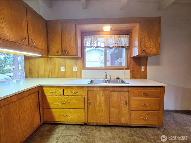 kitchen featuring brown cabinetry, light countertops, and a sink