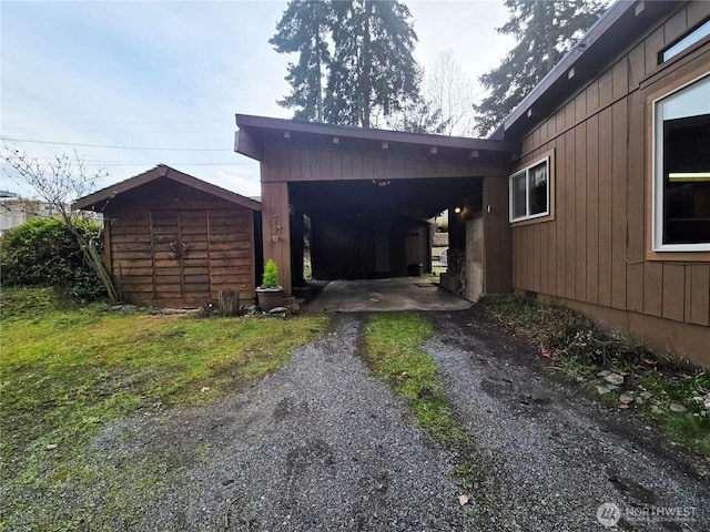 view of side of home with a storage unit, aphalt driveway, and an outbuilding